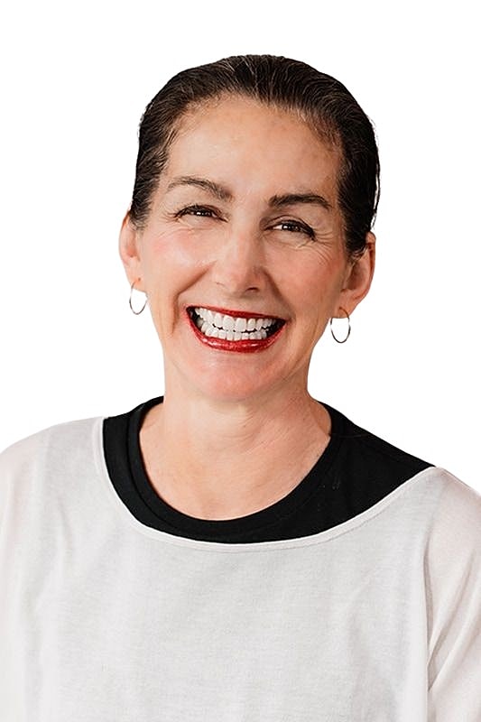 Smiling woman in casual attire with white background.