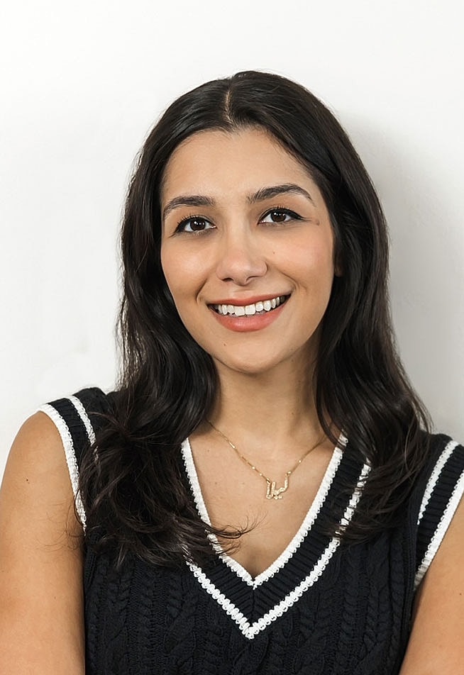 Smiling woman with long dark hair in sweater.