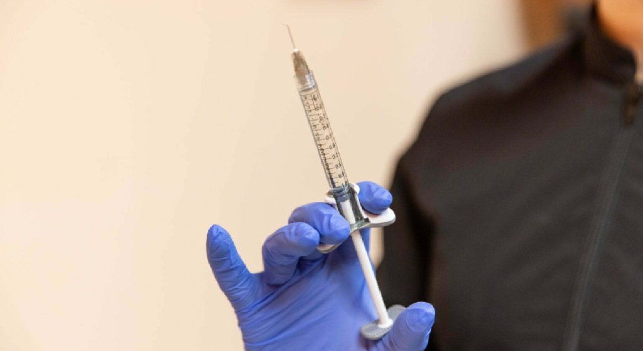 Syringe held by a person wearing gloves.