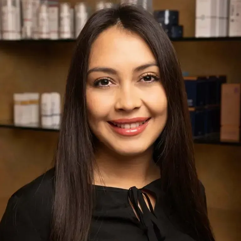 Smiling woman in front of skincare products.